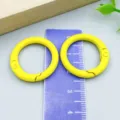 Two yellow painted metal spring O-rings for DIY jewelry making on a measuring scale - Round Spring Buckle (26305) / 1 Piece/Pack (25mm/18mm) / Yellow