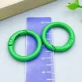 Two green painted round spring buckles displayed over a ruler for bags and jewelry DIY - Round Spring Buckle (26306) / 1 Piece/Pack (25mm/18mm) / Green