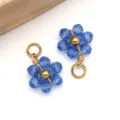 Macro detail of blue crystal flower charms with gold wire wrapping and jump ring - Transparent Light Blue Daisy Crystal Style (T1257)