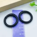 Two black round spring O-ring clasps shown with a purple ruler for size reference - Black