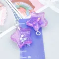 Zwei lila glitzernde Harz-Sternanhänger für DIY-Schmuck auf lila Lineal - 1 Stück (20x18x6mm)