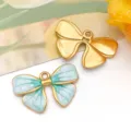 Dos exquisitos dijes de lazo esmaltados para joyería DIY en acabados oro y azul cian - 蝴蝶结吊坠(T1628)
