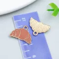 Gold-tone enamel croissant charm for DIY jewelry making, showing size on ruler - Coffee Brown Enamel Bread, Burger & Croissant (24702)