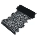 Black lace fabric detail close up showing exquisite floral pattern and delicate eyelash trim. - Black