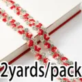 Red and green floral lace ribbon trim close-up shot, delicate embroidery sewing accessory. - Red