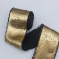 Gold metallic plush ribbon detail close-up showing shimmering texture and frayed black edges. - Black