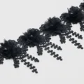 Detailed shot of black 3D flower lace trim, featuring delicate pearl beads and hanging leaves. - Black