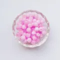 Primo piano dettagliato di perline rotonde in acrilico rosa lucido in ciotola, ideale per gioielli fai da te. - 6mm / Rosa chiaro