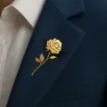 Close-up detail of an elegant gold-colored rose brooch on a dark blue suit lapel - Gold