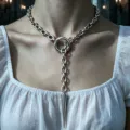 Detalle de un collar gótico en Y plateado con un colgante de punta en una modelo - Collar de Punta / Plateado