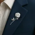 Detail view of a silver-toned stainless steel rose brooch pinned to a navy blue suit lapel. - Silver