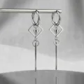 Close-up of punk gothic earrings featuring geometric cones and long silver tassels - Square Cone Tassel Style / Silver