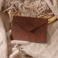 Detailed close-up view of a dark brown textured paper envelope in a cozy vintage setting. - 1 Coffee Envelope