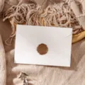 Close-up detail of white envelope with brown wax seal stamp on textured knit fabric backdrop. - White Envelope 1pc + Stamp 1pc