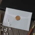 Gros plan détaillé d'une enveloppe en vélin translucide scellée d'un élégant cachet de cire dorée. - 1 enveloppe n° 3 épaissie et 1 sceau à cire