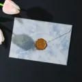 Primo piano dettagliato di una busta marmorizzata blu con sigillo in cera dorata. - 1 busta blu lago + 1 sigillo di cera