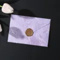 Vista dettagliata della lussuosa busta viola marmorizzata con sigillo di cera dorato per inviti. - 1 busta viola + 1 sigillo di cera