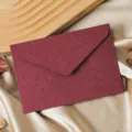 Detailed close-up of a dark red textured paper envelope on golden satin fabric background. - 1 Envelope / Jujube Red