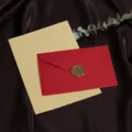 Detailweergave van retro stationery set met rode envelop en decoratief waszegel. - 3 Felroode Enveloppen + 10 Kraft Gelijnde Papieren + 3 Waszegels