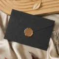 Detailed shot of a black vintage envelope with a gold wax seal on smooth satin fabric. - 1 Envelope + 1 Wax Seal / Charcoal Black