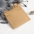 Vue rapprochée de la pochette CD en papier kraft carré posée sur un fond texturé blanc. - 1 Pièce/Paquet / Couleur Papier Kraft