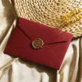 Detailaufnahme des roten Retro-Umschlags mit Leinenstruktur und goldenem Wachssiegel, edel. - 1 weinroter Leinenumschlag & 1 bronzefarbenes Wachssiegel