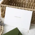 Dettaglio ravvicinato del biglietto di auguri bianco con testo d'amore e pratica busta verde. - 1 Biglietto d'Amore (Senza Busta) / Bianco