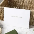 Vista dettagliata di un elegante biglietto d'auguri bianco con testo in un cesto. - 1 Biglietto di Capodanno (Senza Busta) / Bianco