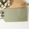 Vue rapprochée et détaillée de la carte d'invitation verte pliée en trois avec sa belle pochette. - Enveloppe en Dentelle Tri-Pli / Vert Avocat