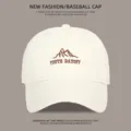 Nahaufnahme der cremeweißen Baseballkappe mit gesticktem Berglogo und Aufschrift. - M (54-59cm) / Gebrochenes Weiß