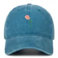 Gros plan d'une broderie de tulipe rose sur une casquette de baseball en denim bleu délavé - Réglable / Bleu lac