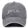 Close-up detail of a washed gray cotton baseball cap with white 'me' cursive embroidery - Adjustable / Gray