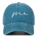 Close-up of washed blue denim baseball cap featuring white cursive 'me' embroidery detail. - Adjustable / Lake Blue