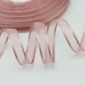 Dettaglio in primo piano del nastro in organza rosa da 10mm, tessuto trasparente per confezioni. - rosa carne