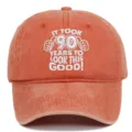 Close-up of "IT TOOK 90 YEARS TO LOOK THIS GOOD!" embroidery on an orange washed cotton cap. - Adjustable / Orange