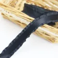 Close-up of black ruffled satin ribbon detail showing delicate pleated edge texture. - Black
