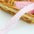 Close-up of pink ruffled ribbon in wicker basket, perfect for floral gift wrapping crafts. - Pink