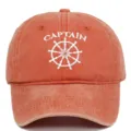 Detail of white Captain embroidery and ship wheel on a washed orange baseball cap - Adjustable / Orange