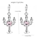 Close-up of silver candlestick earrings decorated with a shiny pink heart crystal. - 14