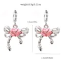 Detailed shot of cute silver bow earrings with pink rose center and dimensions shown. - 1