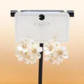 Close-up of white layered floral cluster earrings with sparkling rhinestone centers and gold tone. - C-597 Gold
