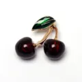 Close-up detail of the elegant cherry brooch featuring shiny red fruit and green leaf. - Silver