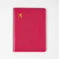 Detailed view of a rose red thick PVC leather passport cover featuring a golden airplane. - Rose Red