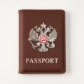 Brown PU leather passport cover detail with metallic double-headed eagle emblem. - Brown