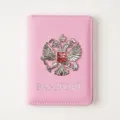 Detail view of the pink PU leather passport cover featuring a metallic double-headed eagle emblem. - Pink