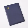 Detail shot of dark blue PU leather passport holder with golden airplane icon, smooth texture. - Passport Cover / Dark Blue
