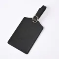 Detailed shot of black PU leather luggage tag featuring debossed adventure quote and buckle. - Black