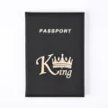 Close-up detail of black PU leather passport cover with white lettering and golden king logo. - Black