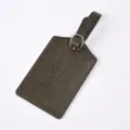 Detailed view of the dark green embossed PU leather luggage tag with metal buckle and travel quote. - Olive Green