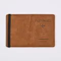 Detail shot of brown PU leather passport holder travel wallet with elastic band and airplane print. - Amber